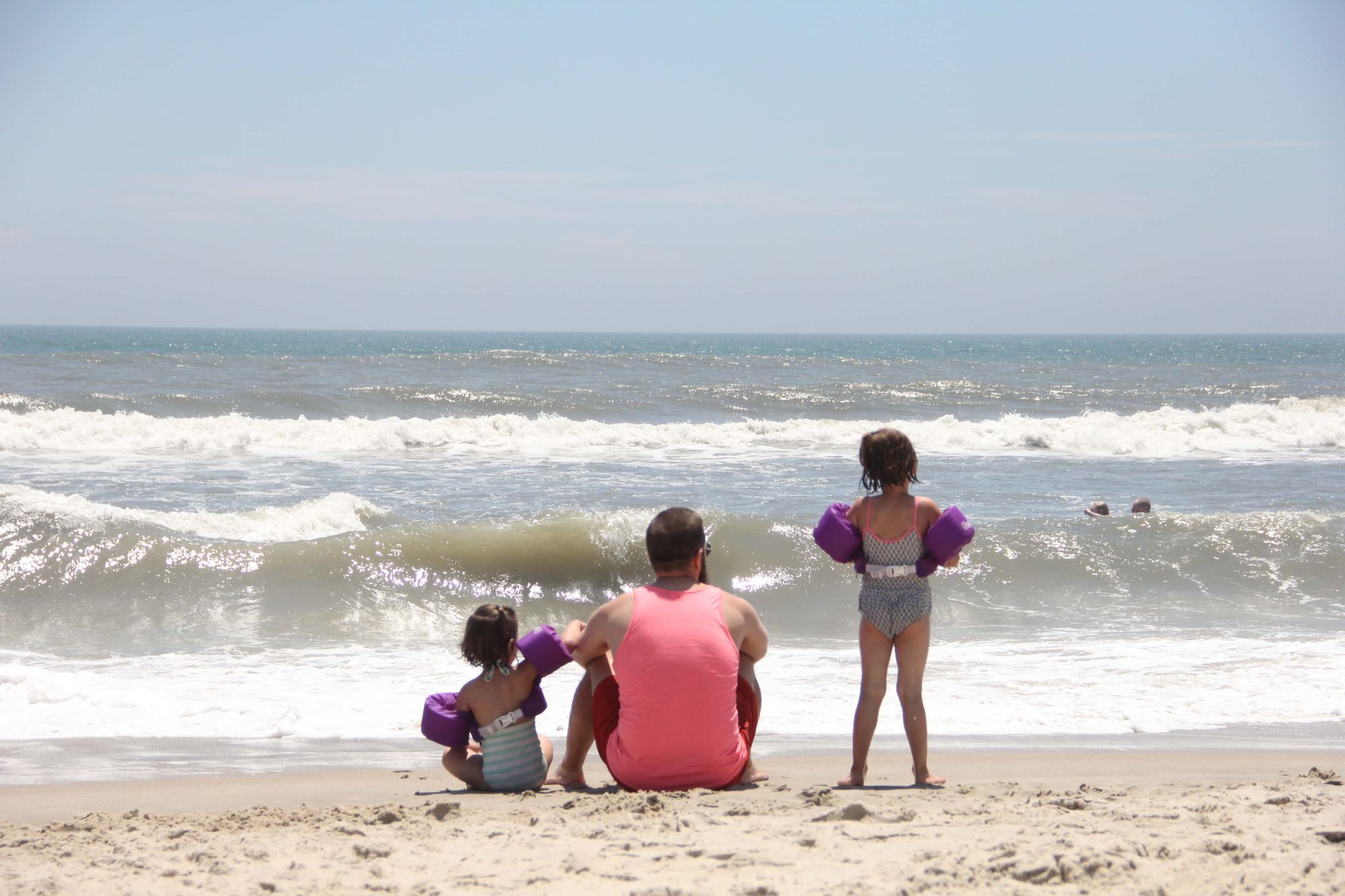 A dad and his daughters watching the Atlantic waves crashing on the Assateague beach.